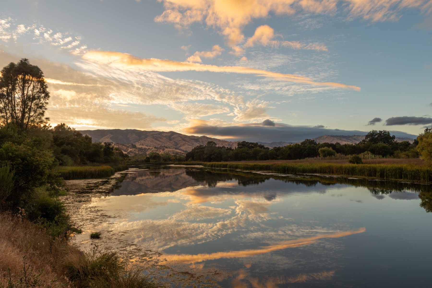 Sunset over a still waterway outside Woodland, with the sky reflected in the water.